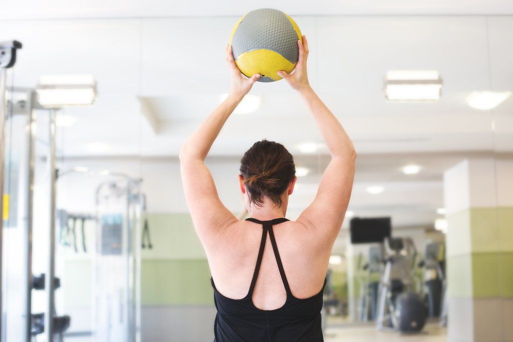 Exercise ball home gym woman lifting ball in home gym