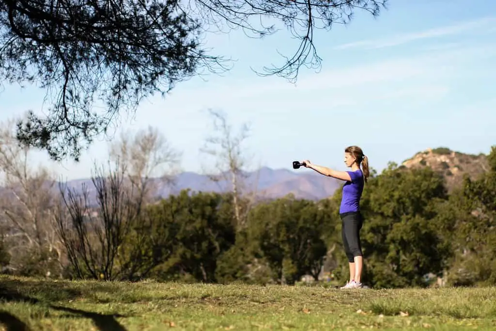 Kettlebell swings performed by a woman in an open outdoor field