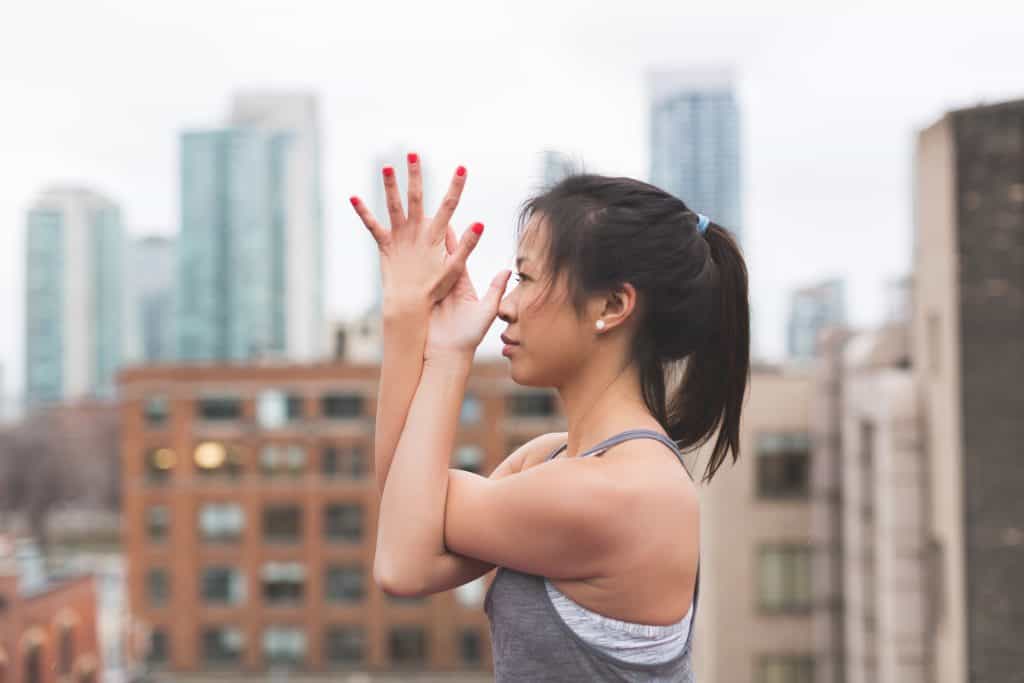 fitness_001 Girl in a ponytail and workout clothes stretching on a rooftop prior to working out
