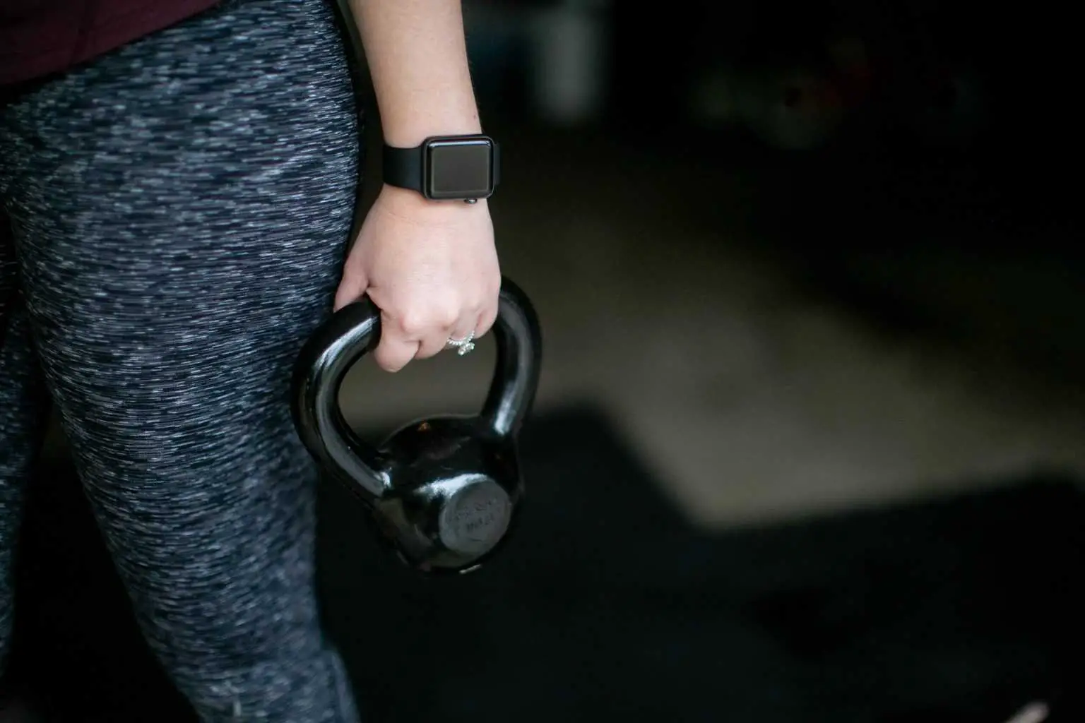 Person wearing a fitness watch while holding a kettlebell with one hand