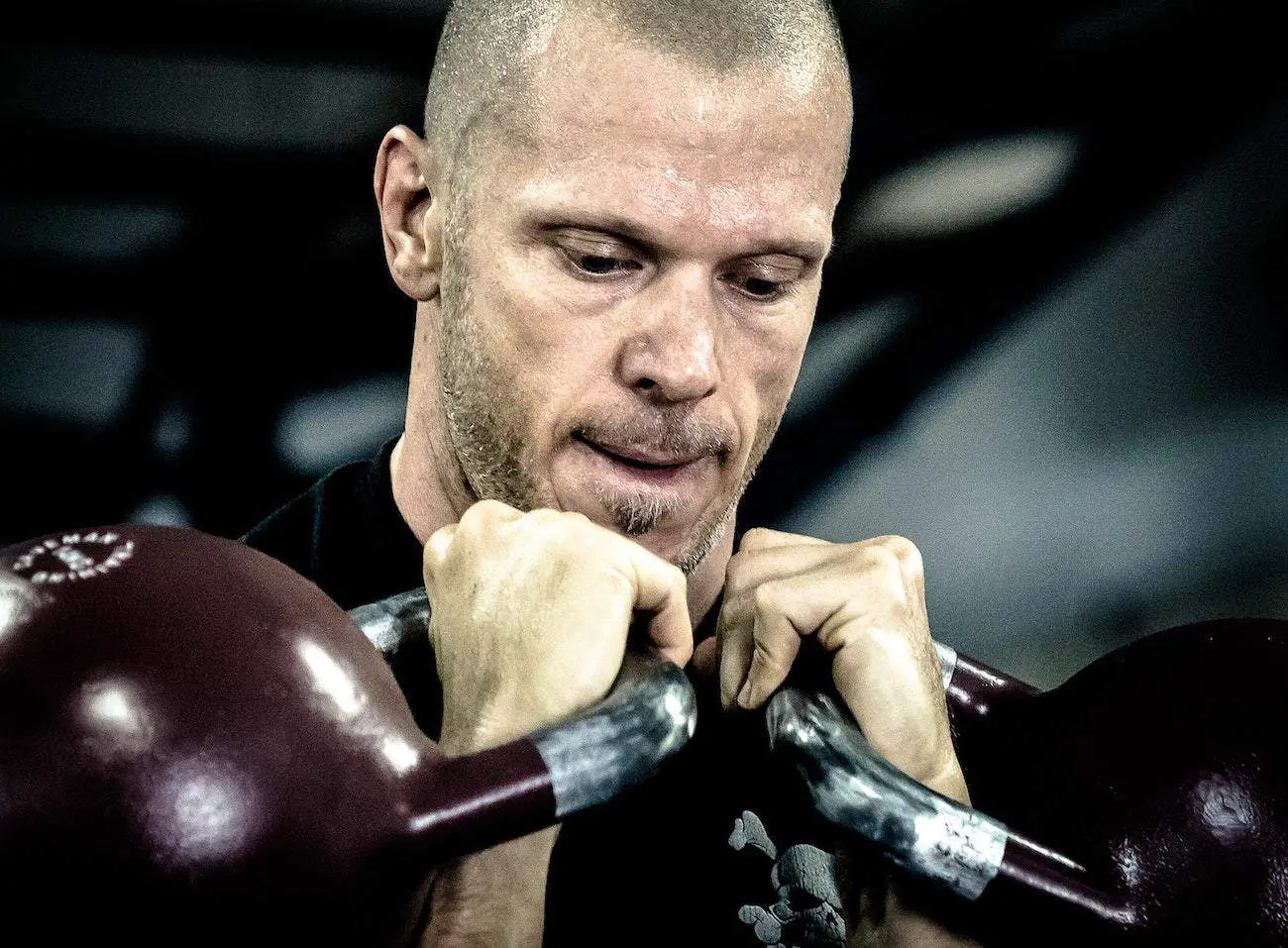 Man holding two kettlebells close to his chest