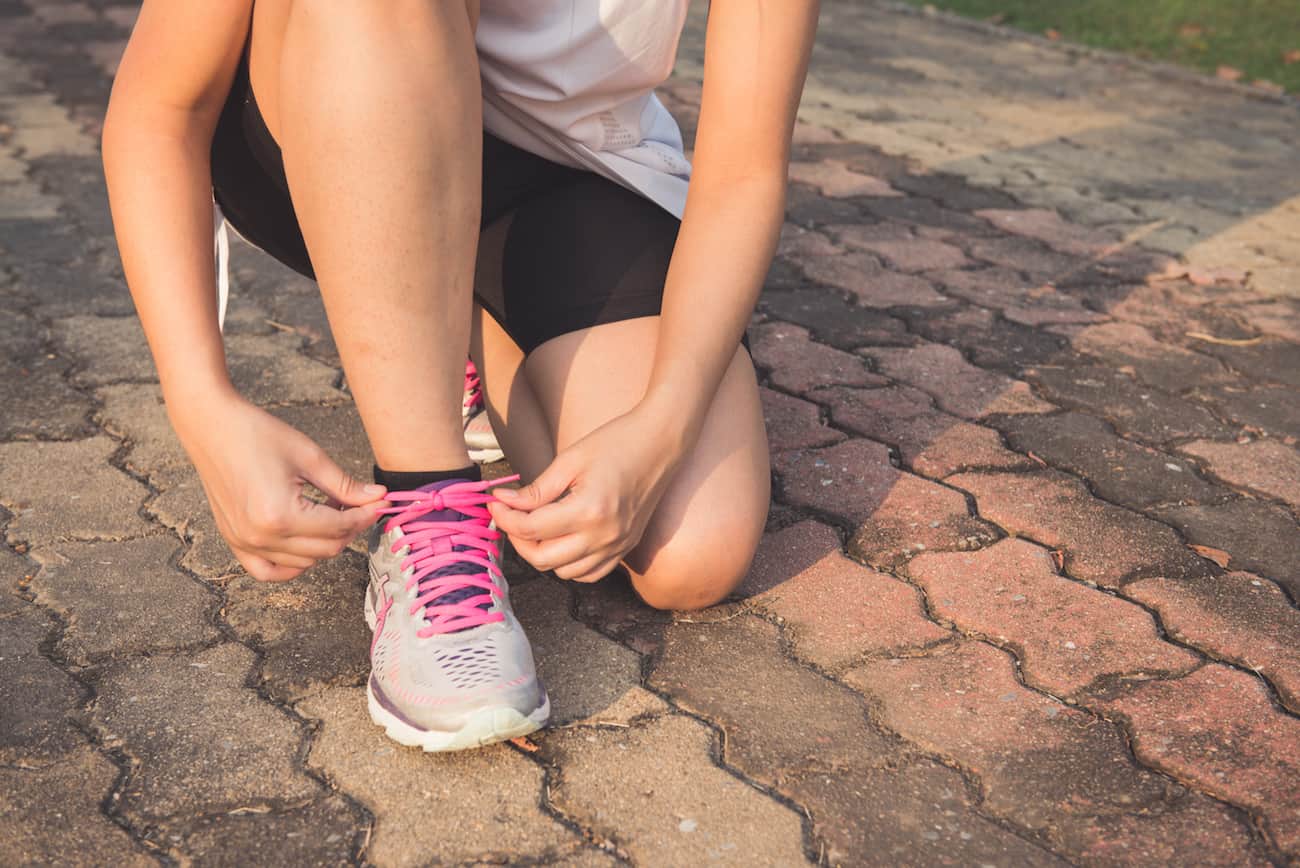 Person crouching down to tie their shoelaces