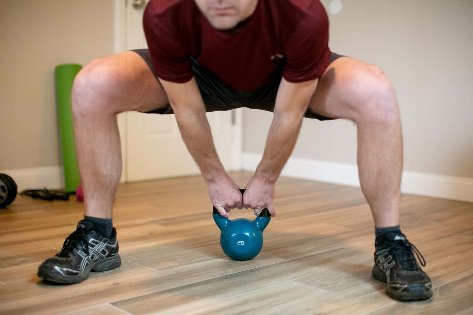 Man trying to lift a heavy kettlebell from the floor with both hands