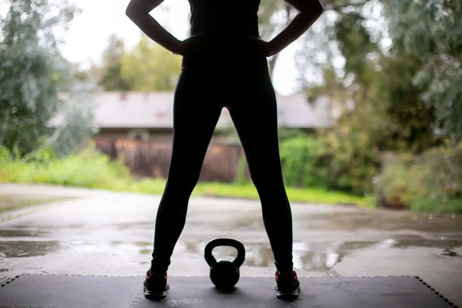 Silhouette of woman in her garage gym with a kettlebell