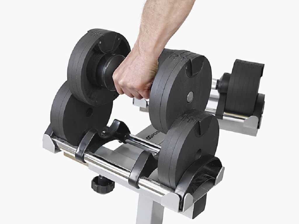 Man's hand carrying a black adjustable dumbbell from it's case