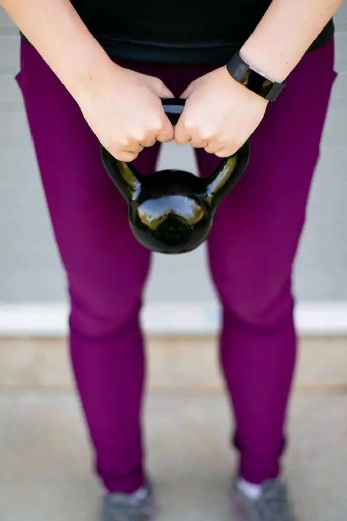 Close up of a black kettlebell in young woman's arms