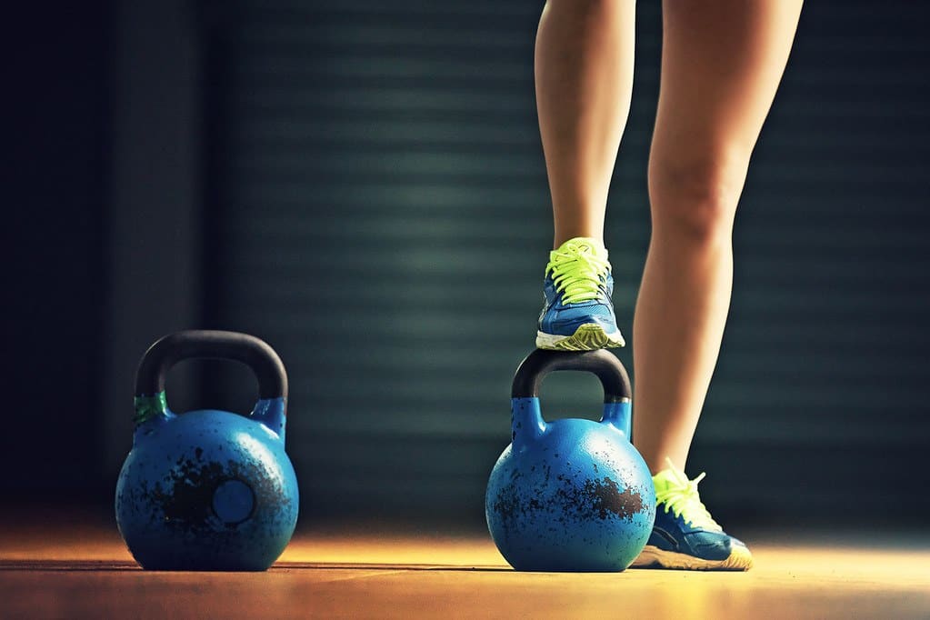 beginner-kettlebell-workout-1 A woman prepares to workout with two kettlebells in a gym