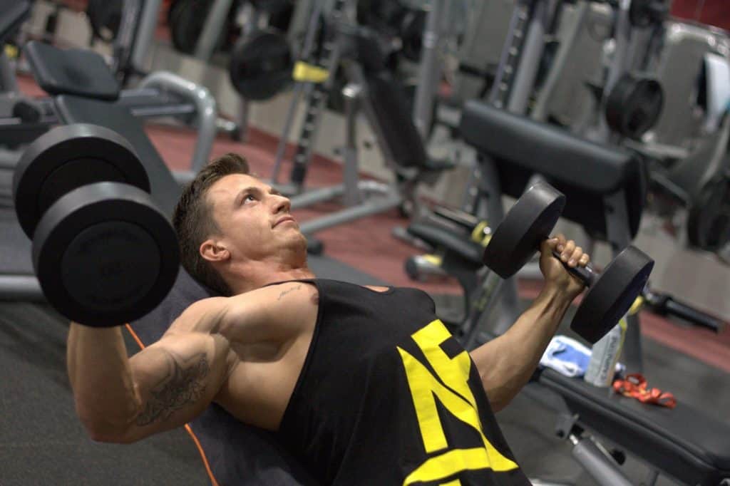 Man lying on a bench working out with dumbbells