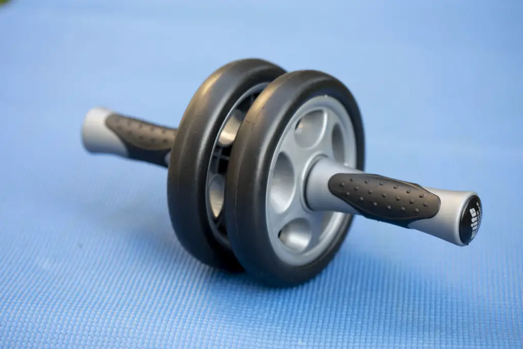 A close up image of an ab roller placed on a blue yoga mat