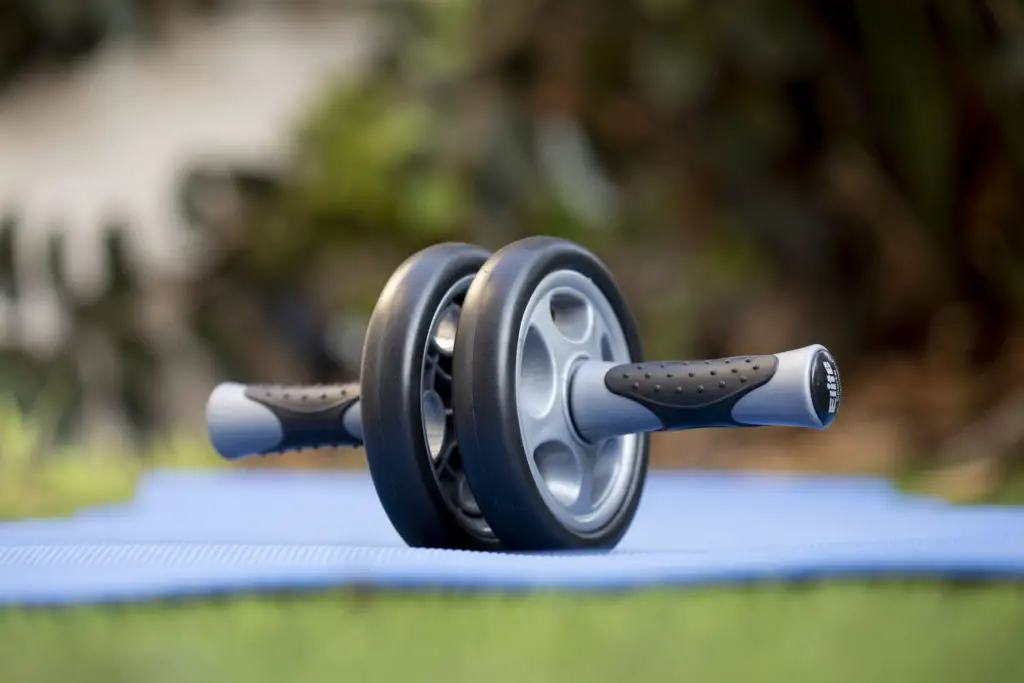 Ab roller placed on a blue yoga mat outside