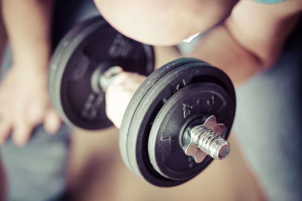 Man showing how an adjustable dumbbell works by lifting it with his hands