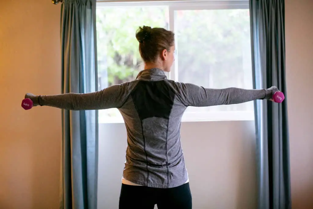 Woman lifting dumbbells parallel to her shoulders