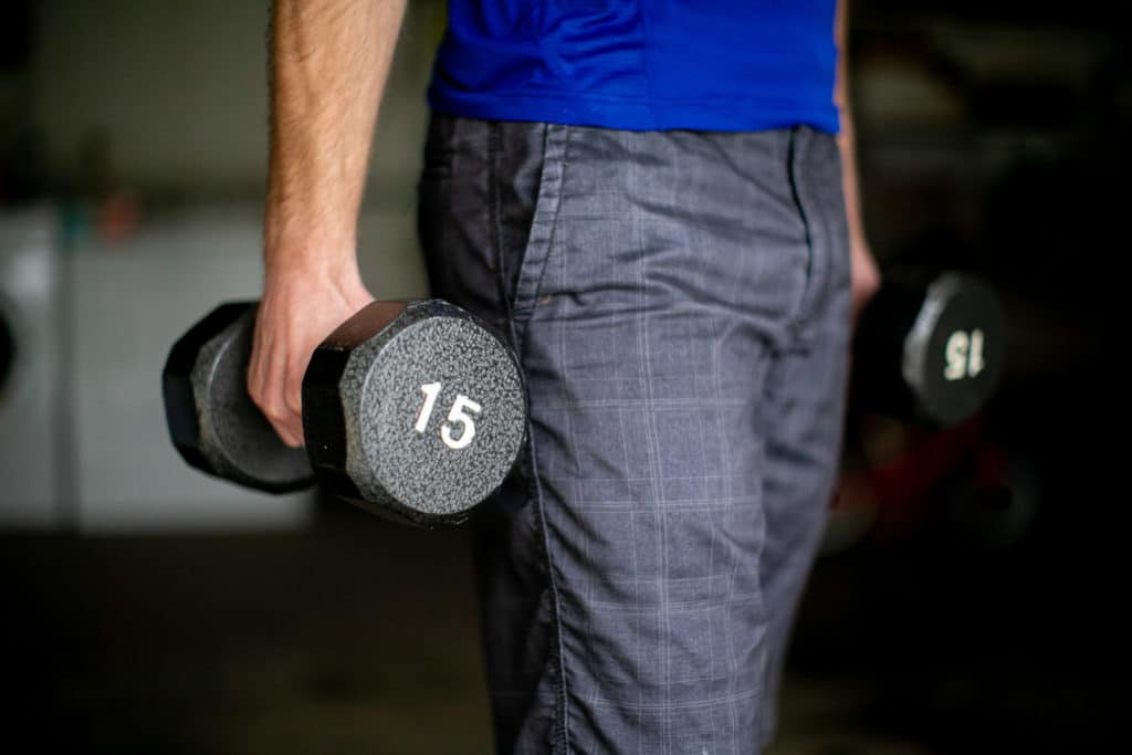 Man holding dumbbells in his personal gym in his garage