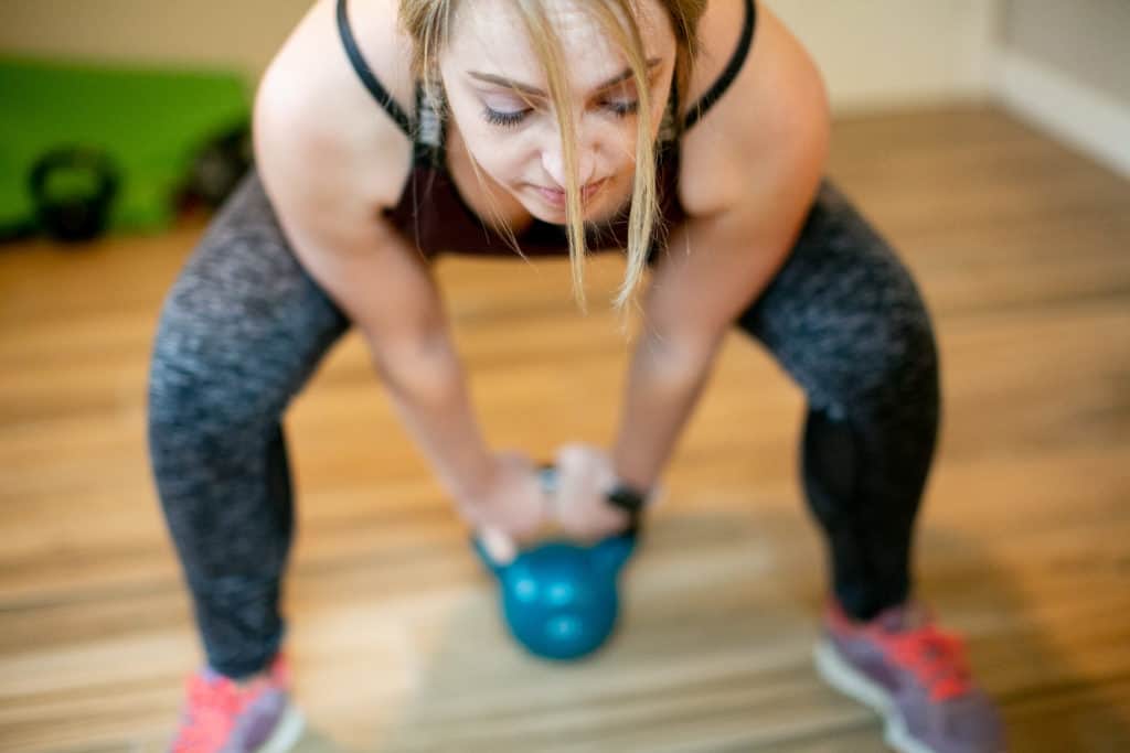 Woman trying to lift a kettlebell with both hands