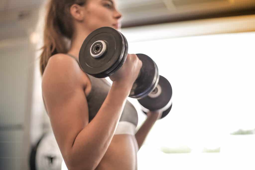 Woman holding dumbbells with both hands while performing her exercise reps