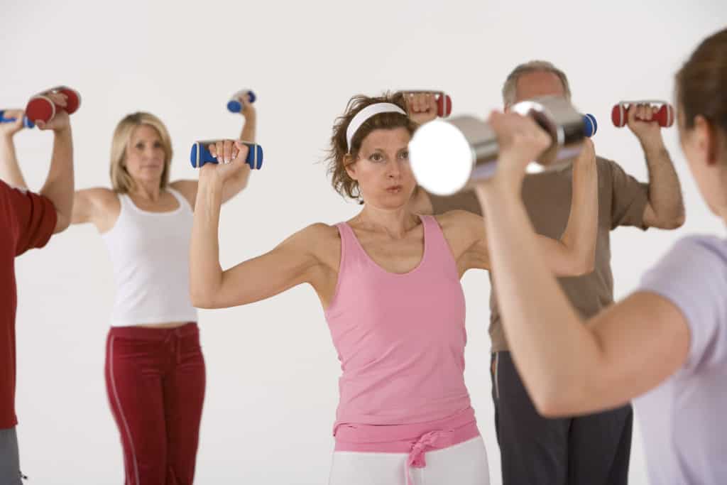 Group of people lifting dumbbells with both hands hoping to get stronger with dumbbell exercises
