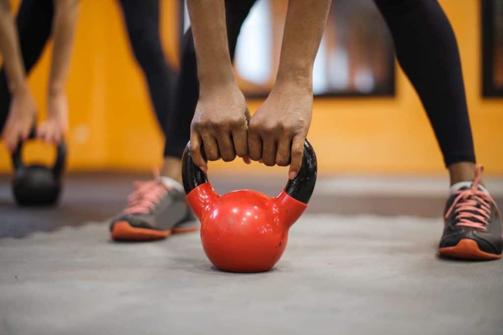 Person bending and holding a red kettlebell