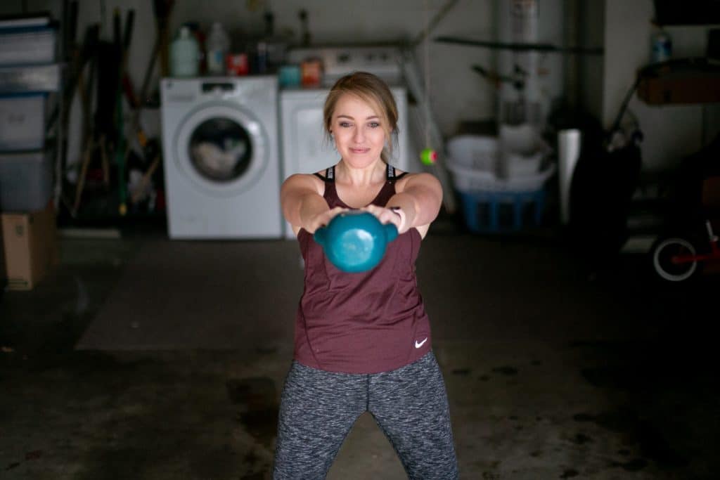 Woman swinging a kettlebell towards her front body with both hands 