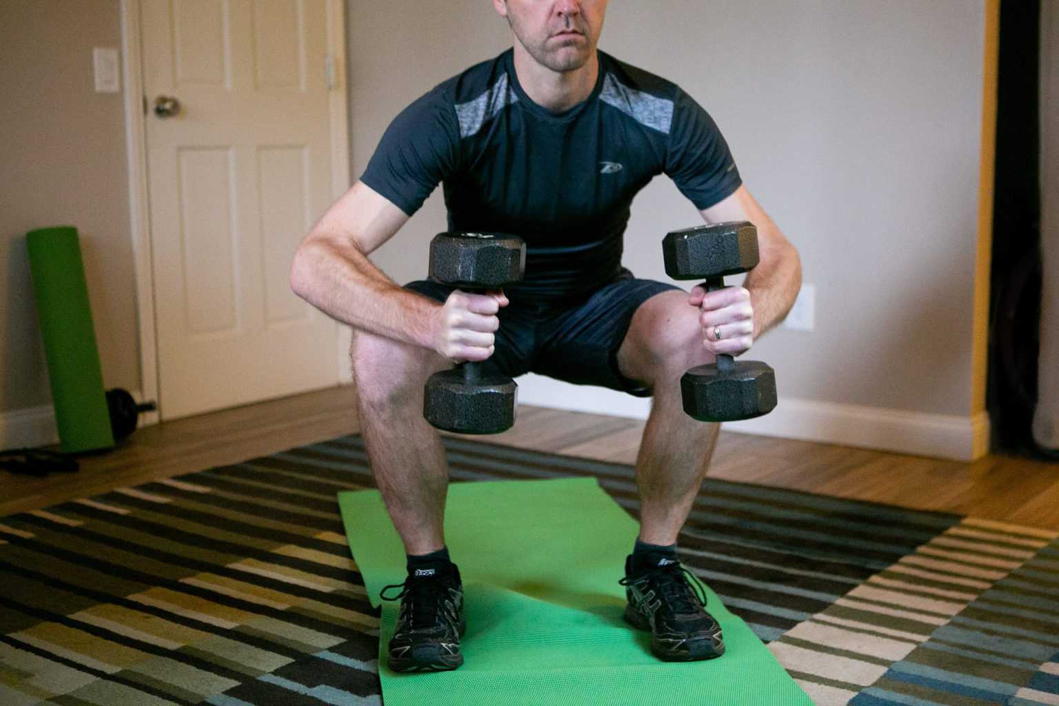 Man doing dumbbell squats while holding dumbbells with each hand