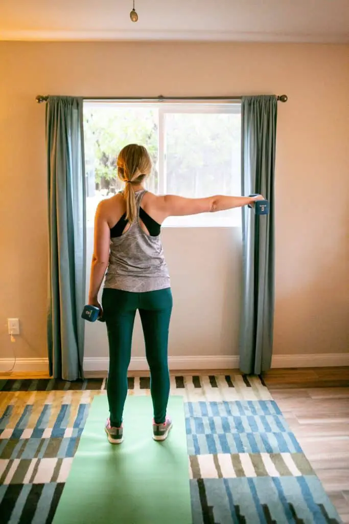 Woman lifting a dumbbell in one side, while holding down another