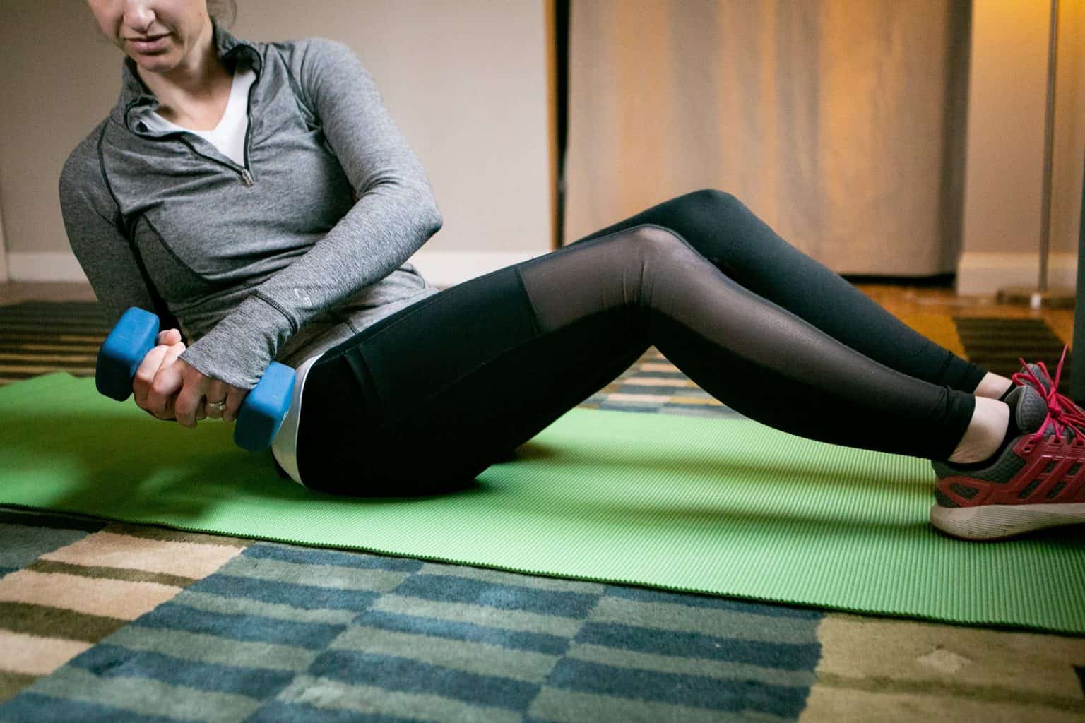 Woman sitting down while holding a dumbbell sideways