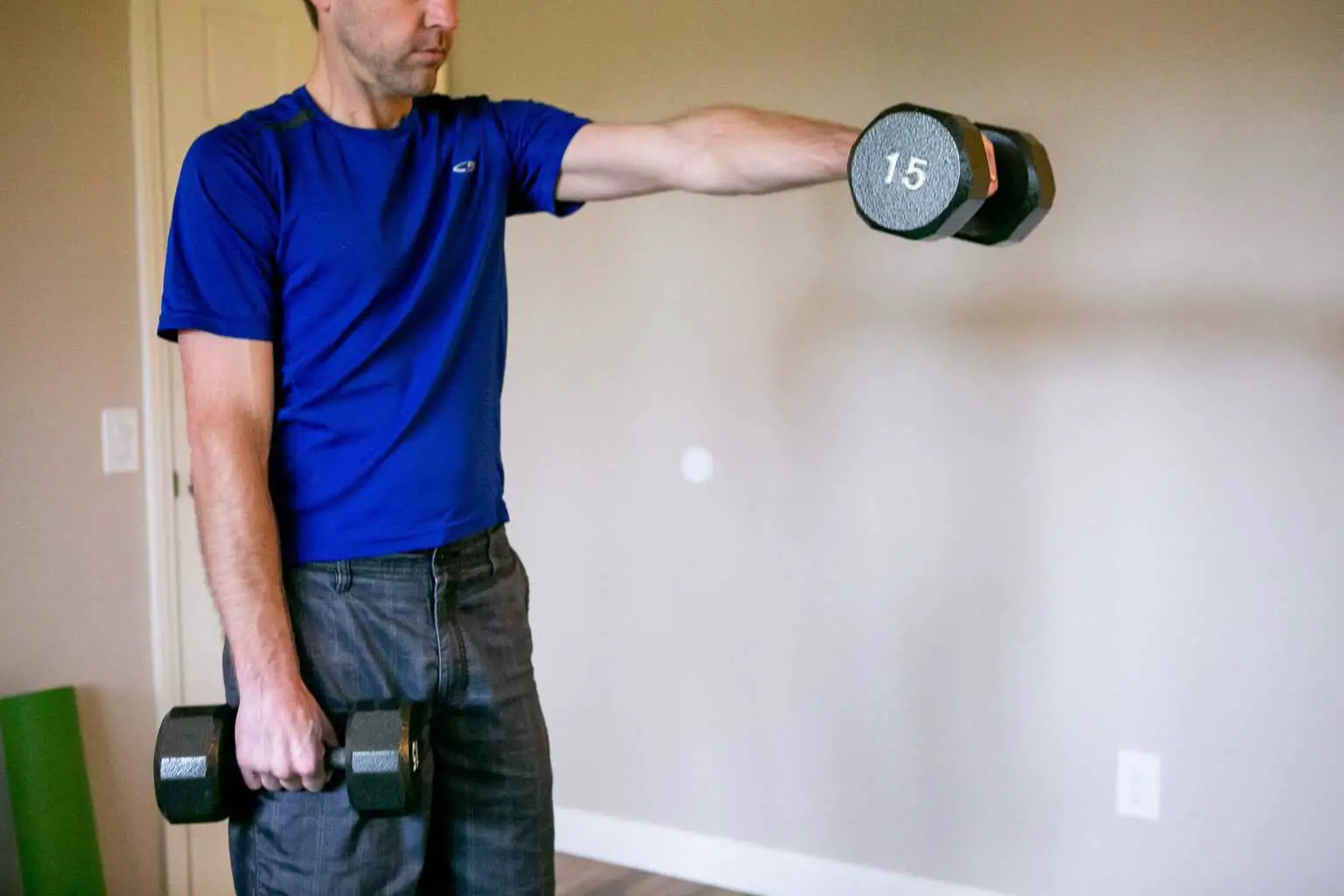 Man lifting a dumbbell while the other hand is holding another one on his side