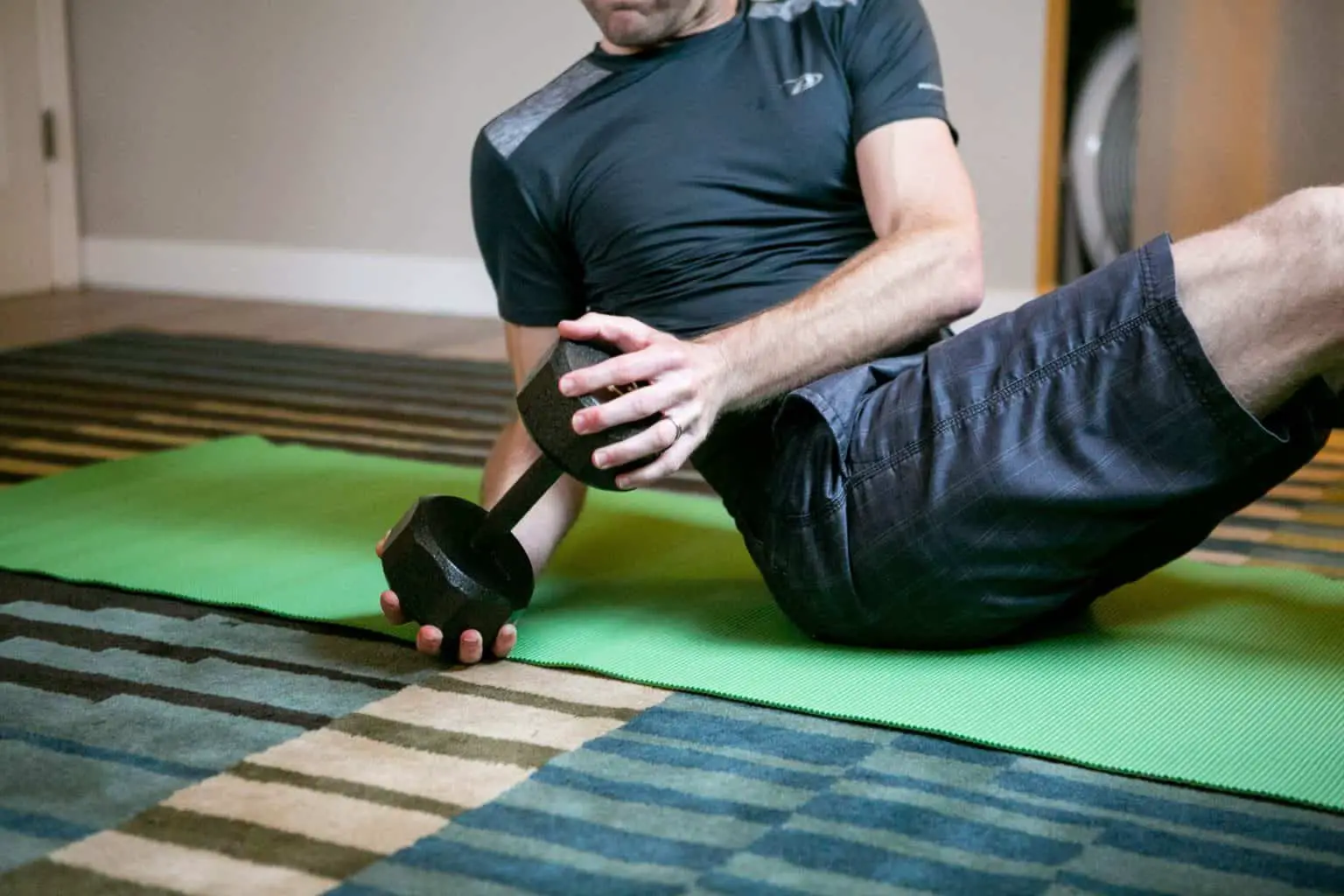 Man sitting down while holding a dumbbell sideways