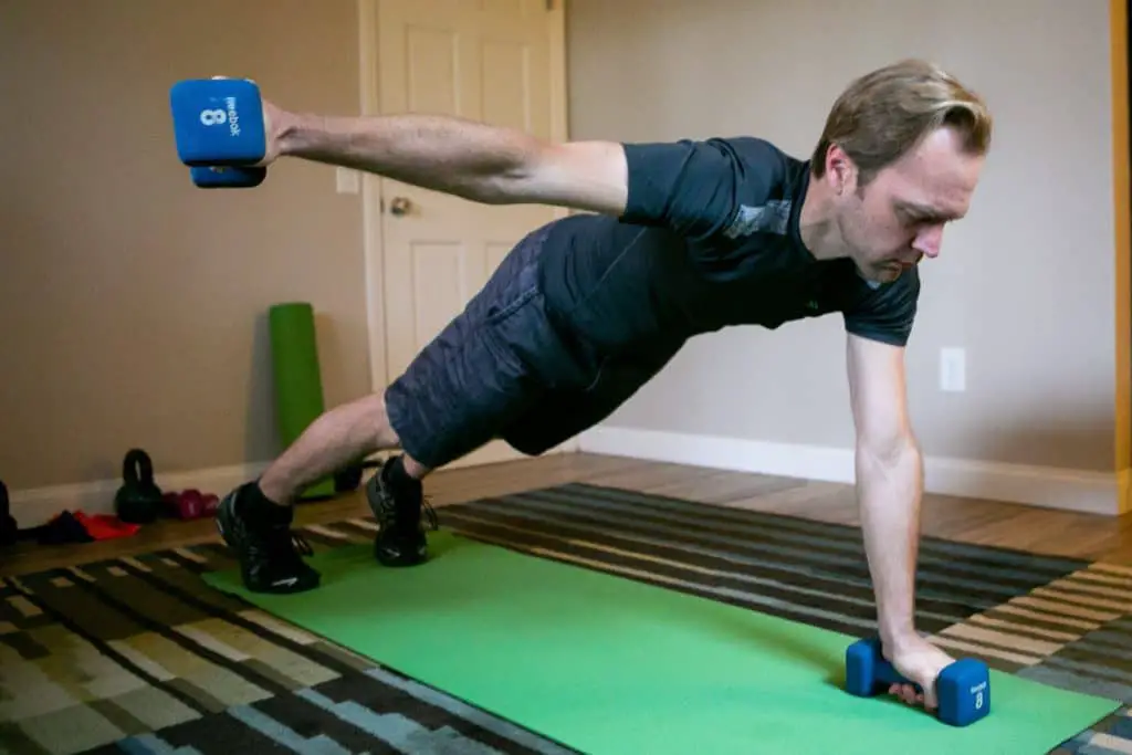 Man doing planks while holding dumbbells with each hand