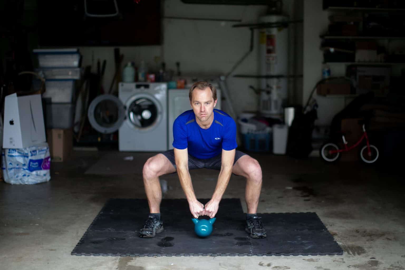 Man trying to lift a heavy kettlebell from the floor with both hands