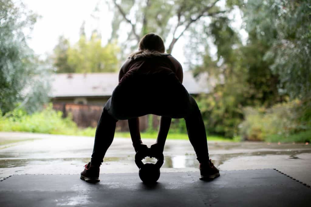 Silhouette of a person trying to lift a kettlebell on the floor