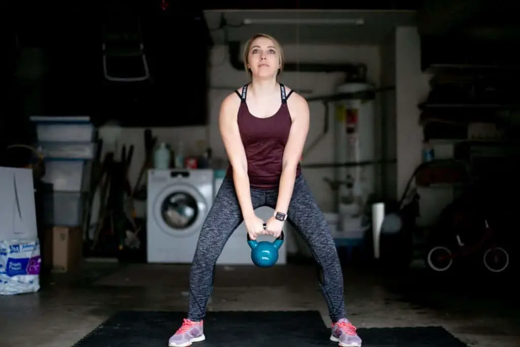 Woman trying to lift a kettlebell from the floor with both hands