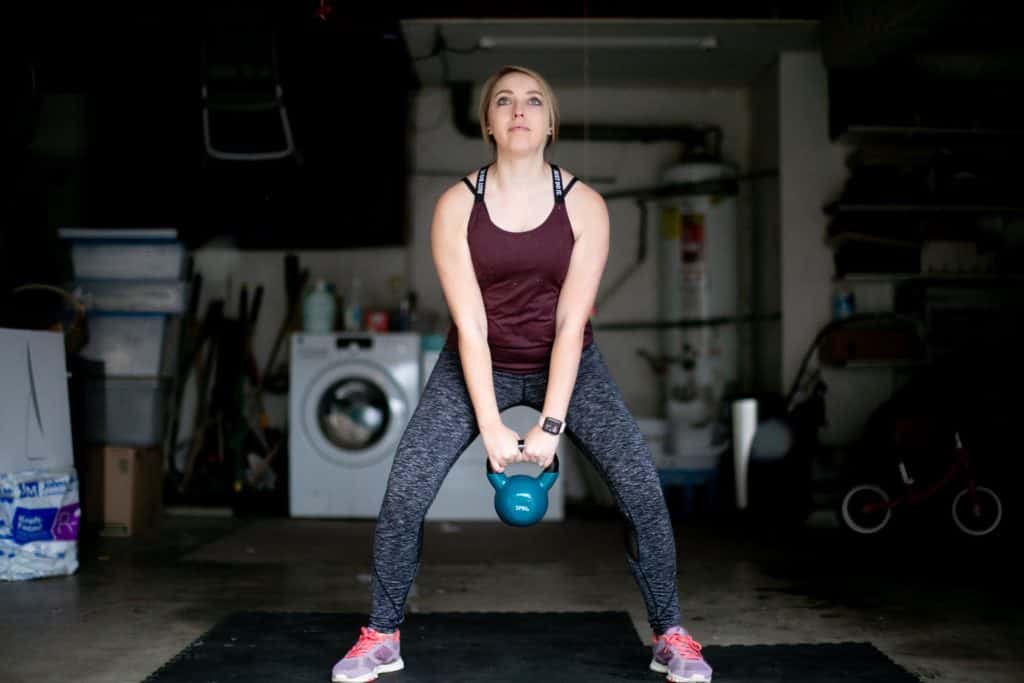 Woman trying to lift a kettlebell from the floor with both her hands