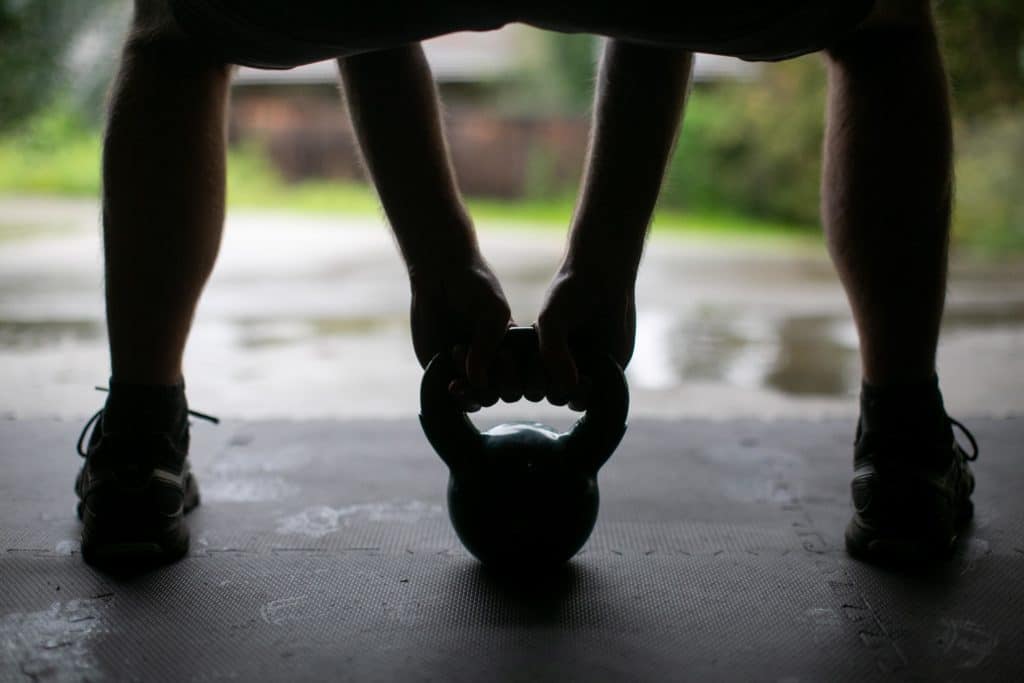 Silhouette of a person trying to lift a kettlebell on the floor