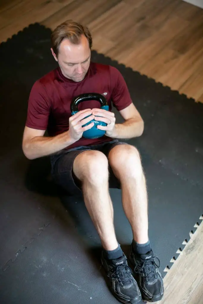 Man doing crunches while holding a kettlebell with both hands