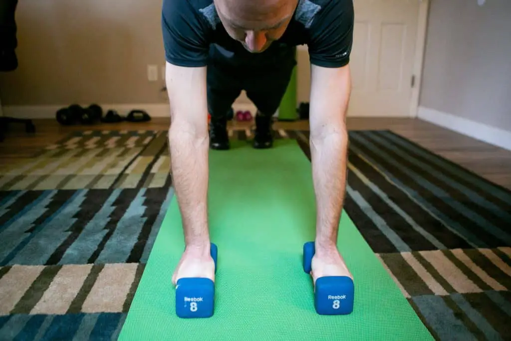 Man performing dumbbell exercises on his home gym