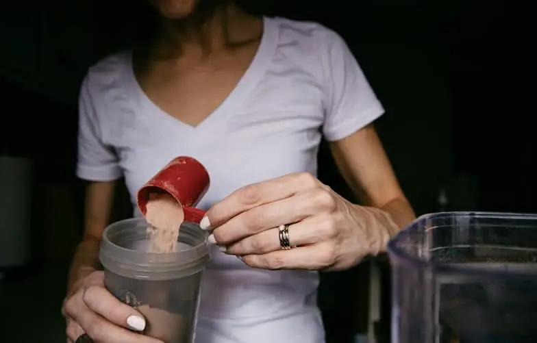 Person preparing her protein powder to gain weight without side effects