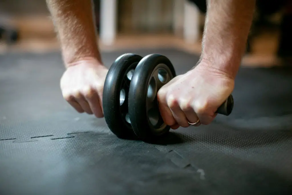 Close up of a person using an ab roller on a fitness mat