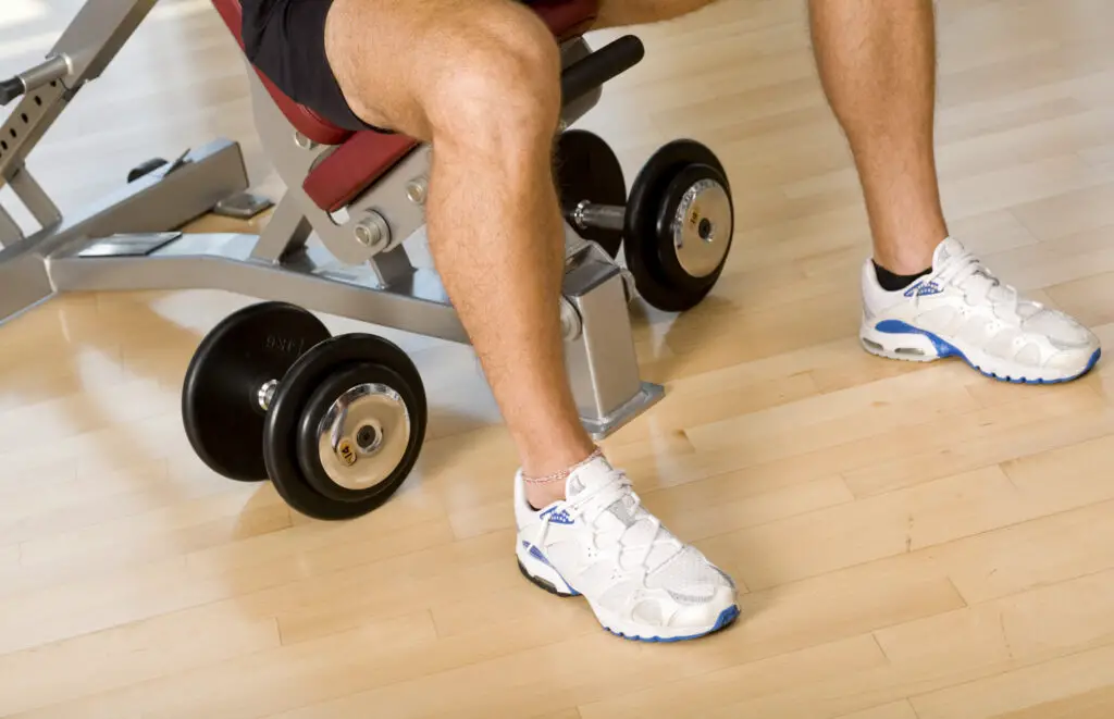 Man sitting on a weight bench with hand weights at his feet