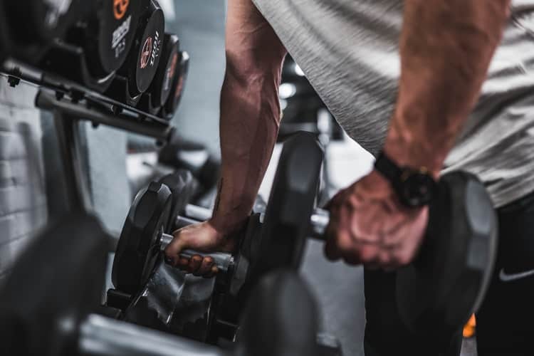 Man trying to lift dumbbells from a rack