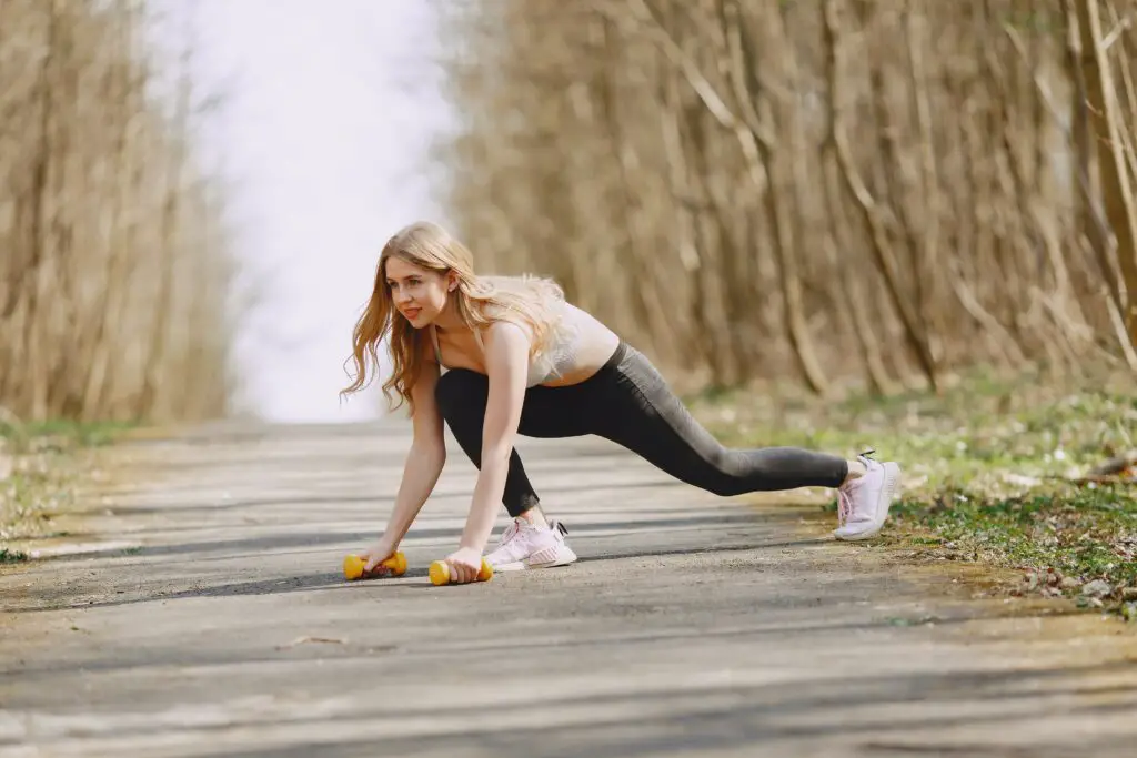 Woman about to do a renegade row, one of the 3 best bicep dumbbell exercises