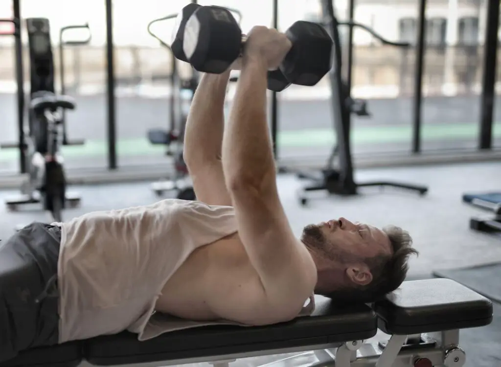 Man lying in a bench lifting dumbbells