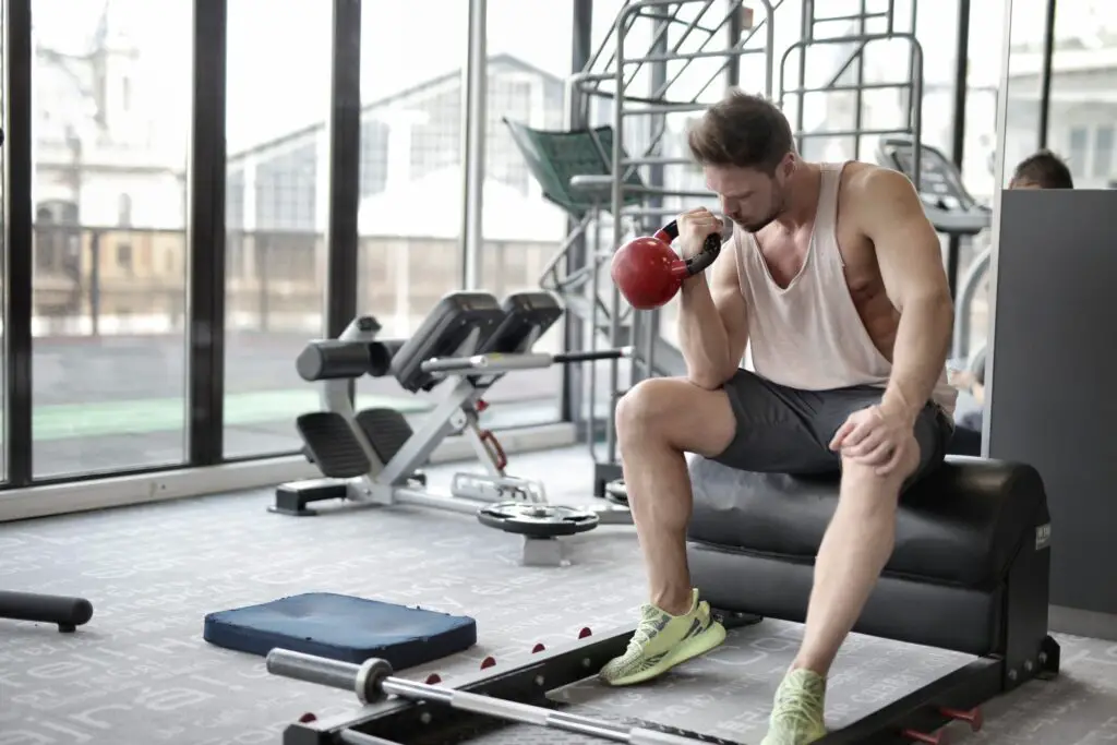 Man sitting down trying to lift a kettlebell with one hand