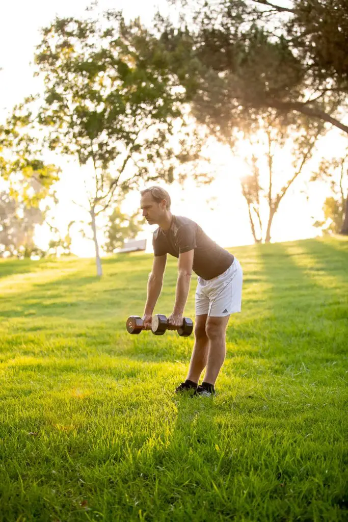 Man trying to lift dumbbells with each hands