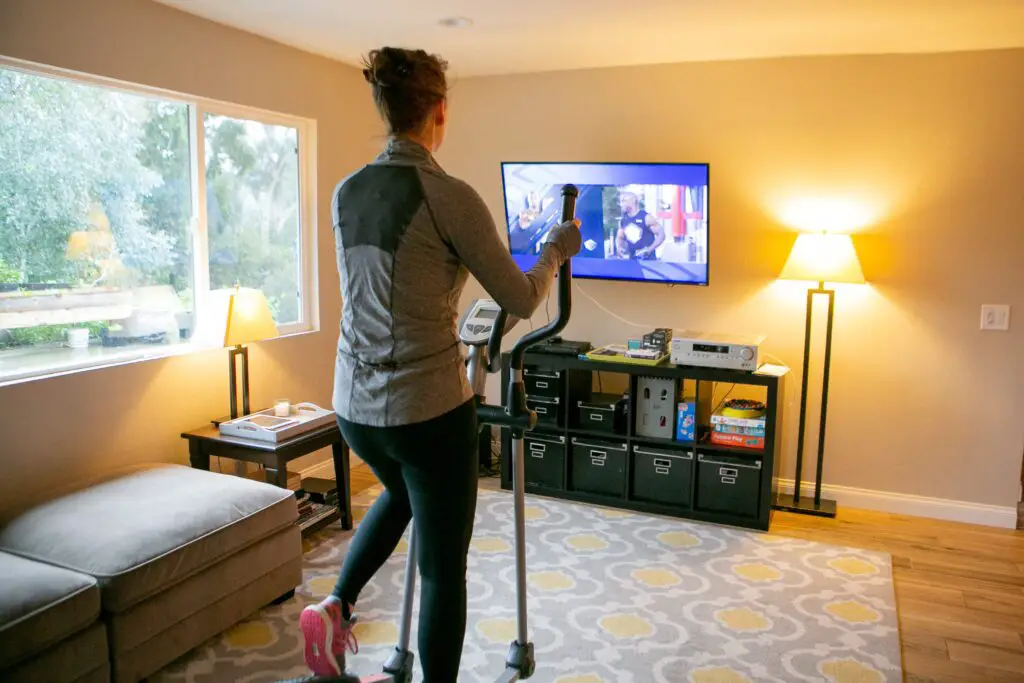 Woman using an exercise bike while watching tv