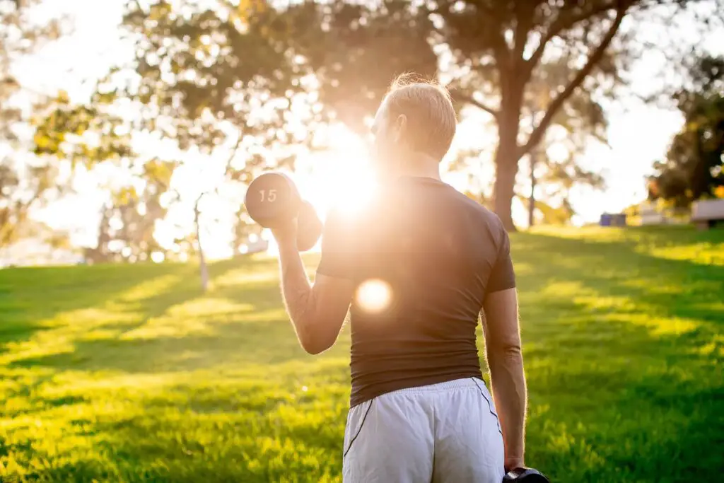 Man lifting a dumbbell with one arm while holding the other pair on his side