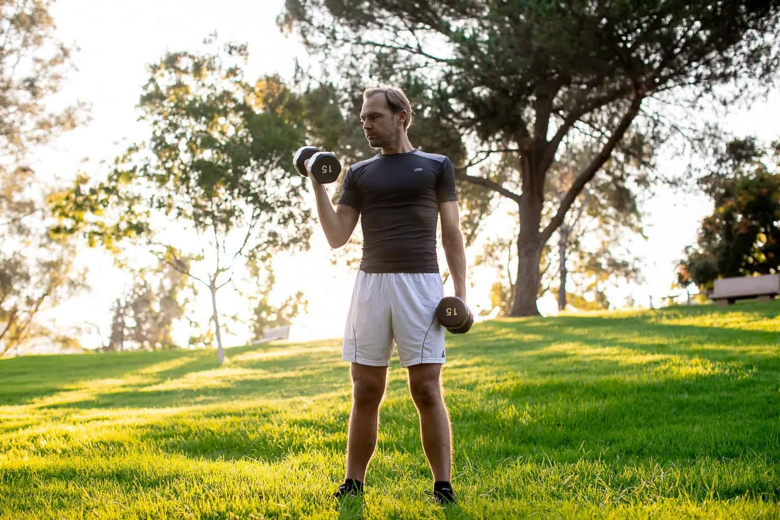 Man lifting a dumbbell with one arm while holding the other pair on his side