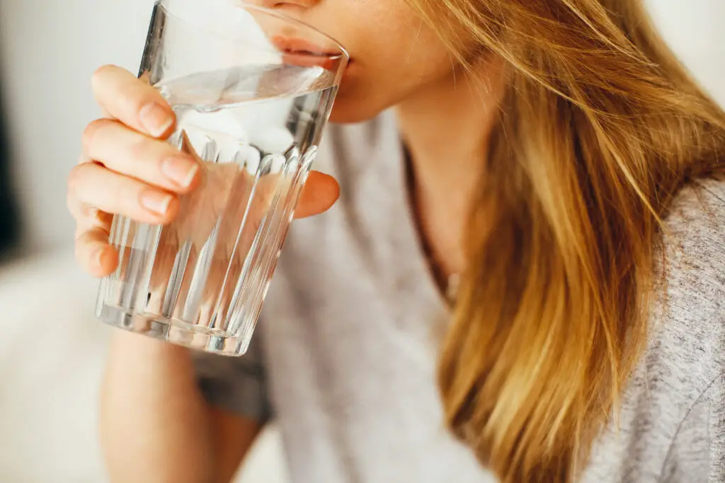 Woman trying to get her pre workout supplements out of her system by drinking water