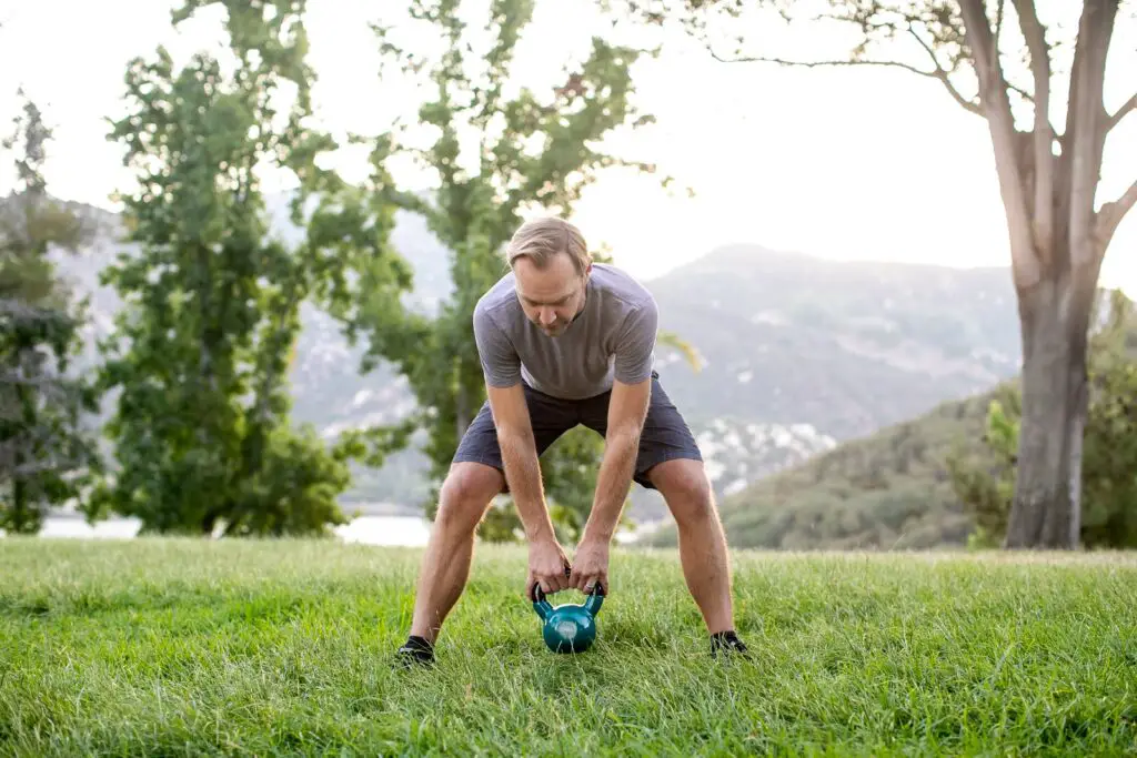 Man trying to lift a kettlebell with both hands