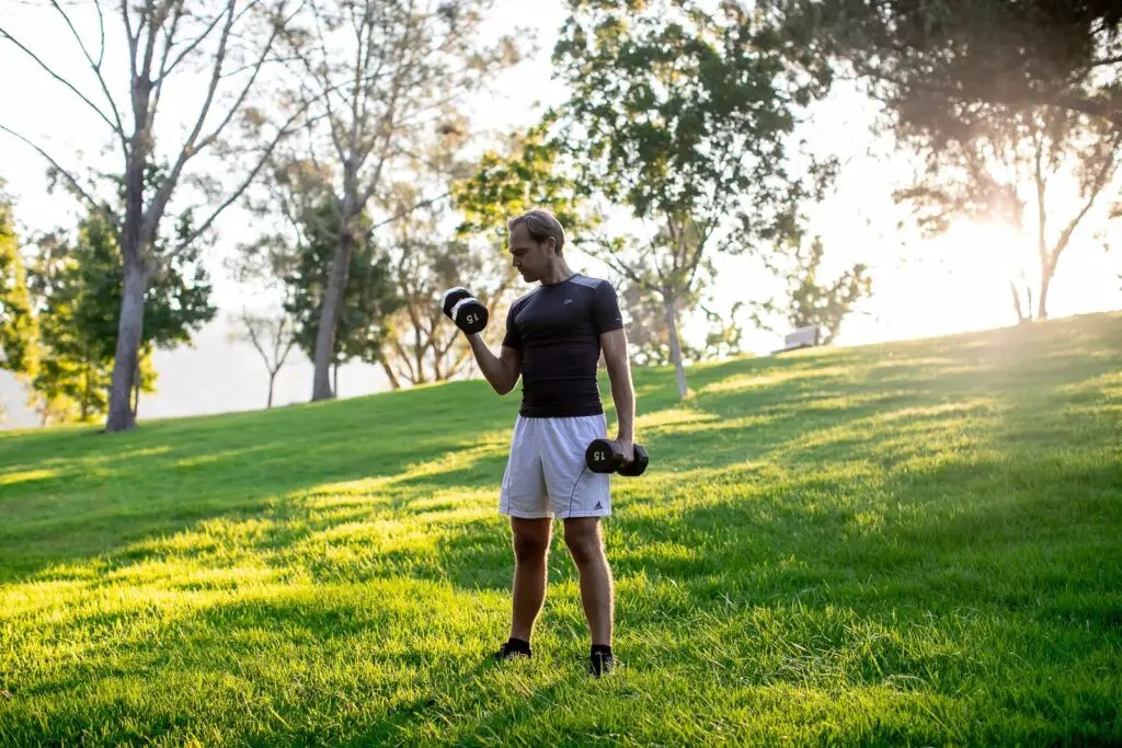 Man lifting a dumbbell with one arm while holding the other pair on his side