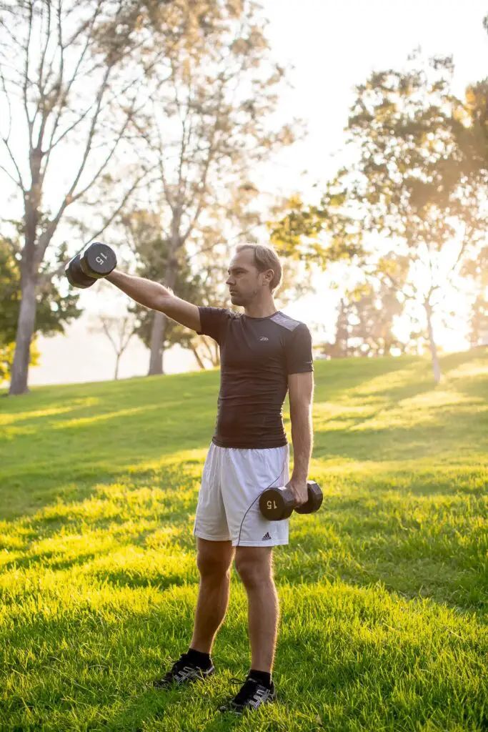 Man lifting a dumbbell with one arm while holding the other pair on his side